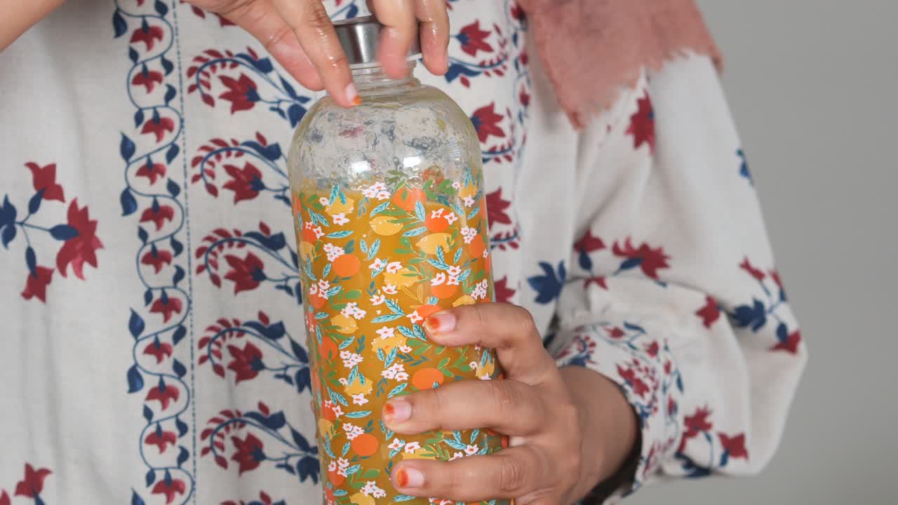 Woman holding a patterned glass bottle