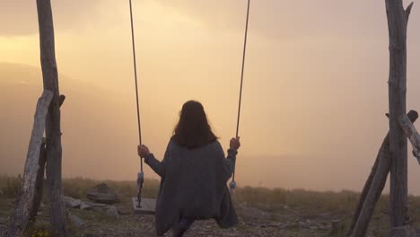 woman swinging on a swing in lousa baloico at sunset, portugal