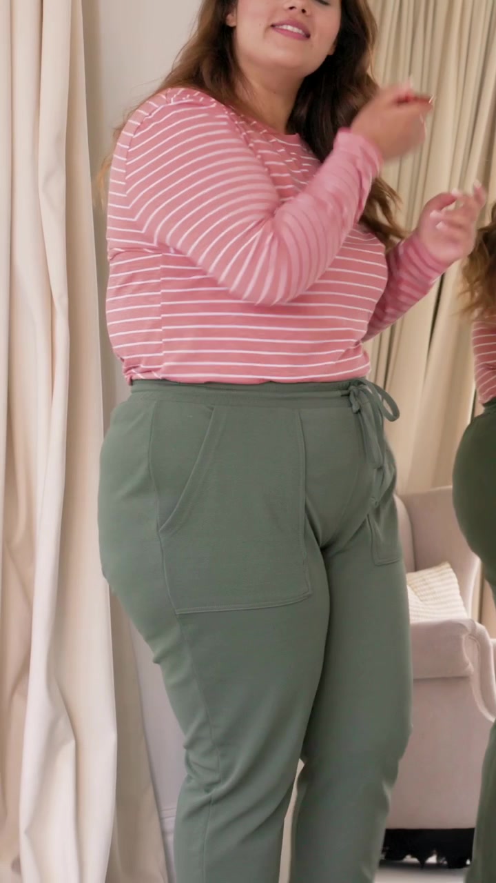 Video verticale: Donna con top rosa di fronte allo specchio in camera da letto, si trucca con un pennello per un film.