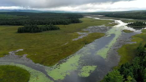 aerial shot dropping down above the still waters of shirley bog winding through the maine countryside under ominous stormy skies