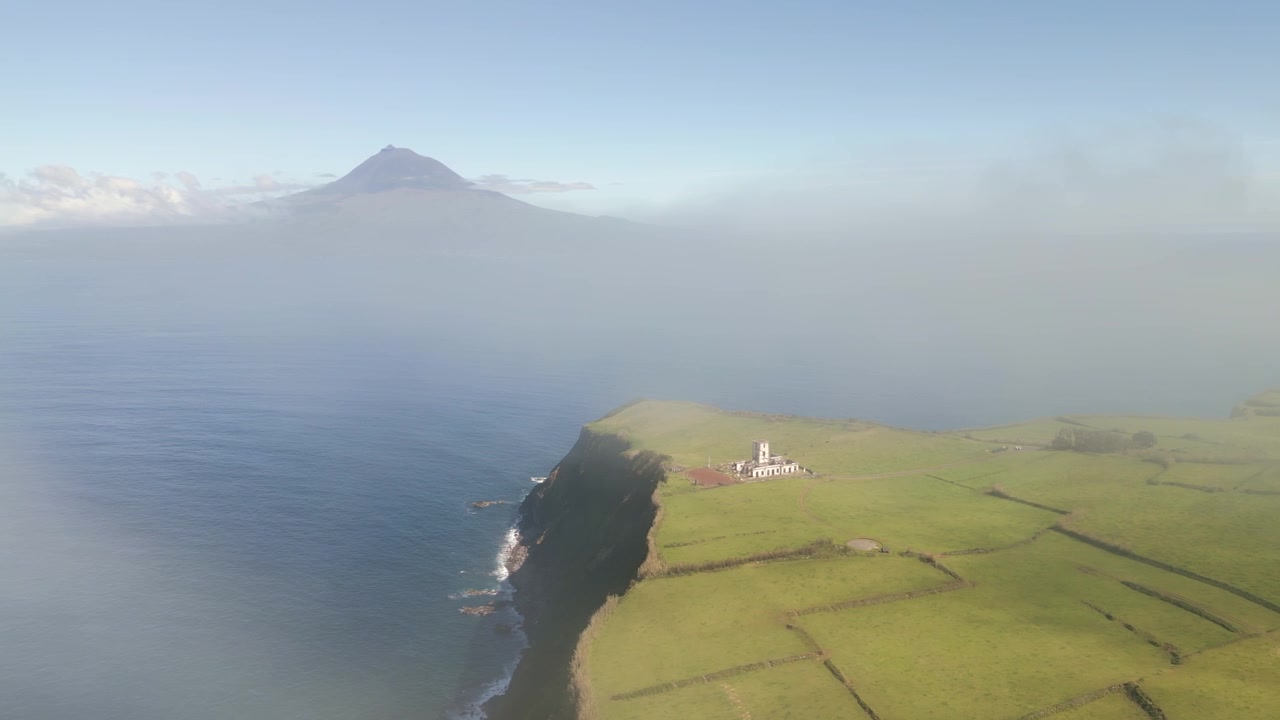 Promontorio con nuvola nebbiosa che oscura parzialmente il paesaggio prima di rivelare un faro costiero. Paesaggio costiero naturale con condizioni meteorologiche suggestive, vista aerea