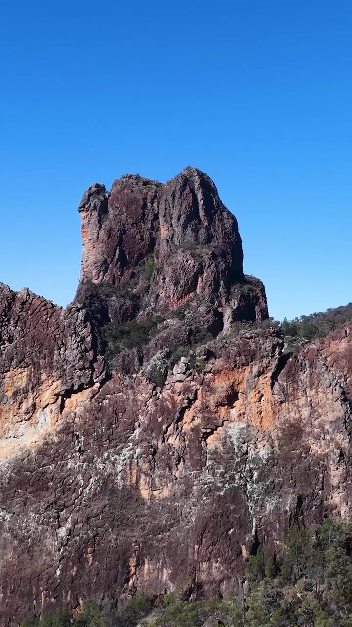 Panoramica di scogliere vulcaniche frastagliate e cime montuose sotto un cielo azzurro e limpido.