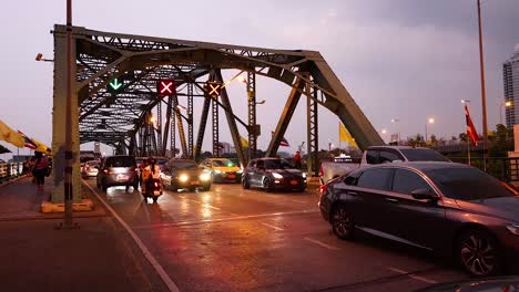 vehicles and motorcycles crossing a busy bangkok bridge