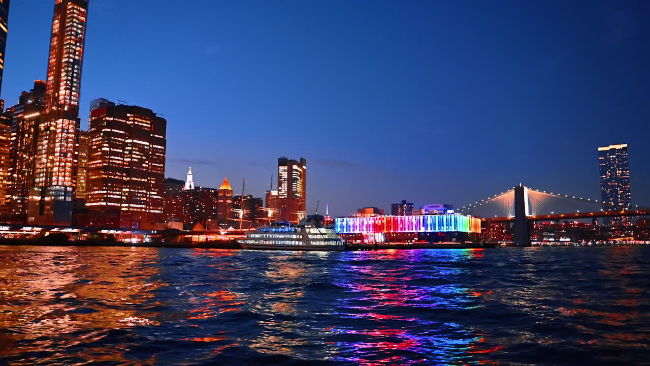 Illumination of stunning New York reflecting in the riverscape. Footage at the pier of metropolis at night time