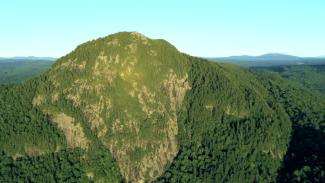 Aerial-drone-shot-flying-looking-out-over-Bore-Mountain-above-thick-green-woods-and-lakes-in-the-vast-Maine-wilderness