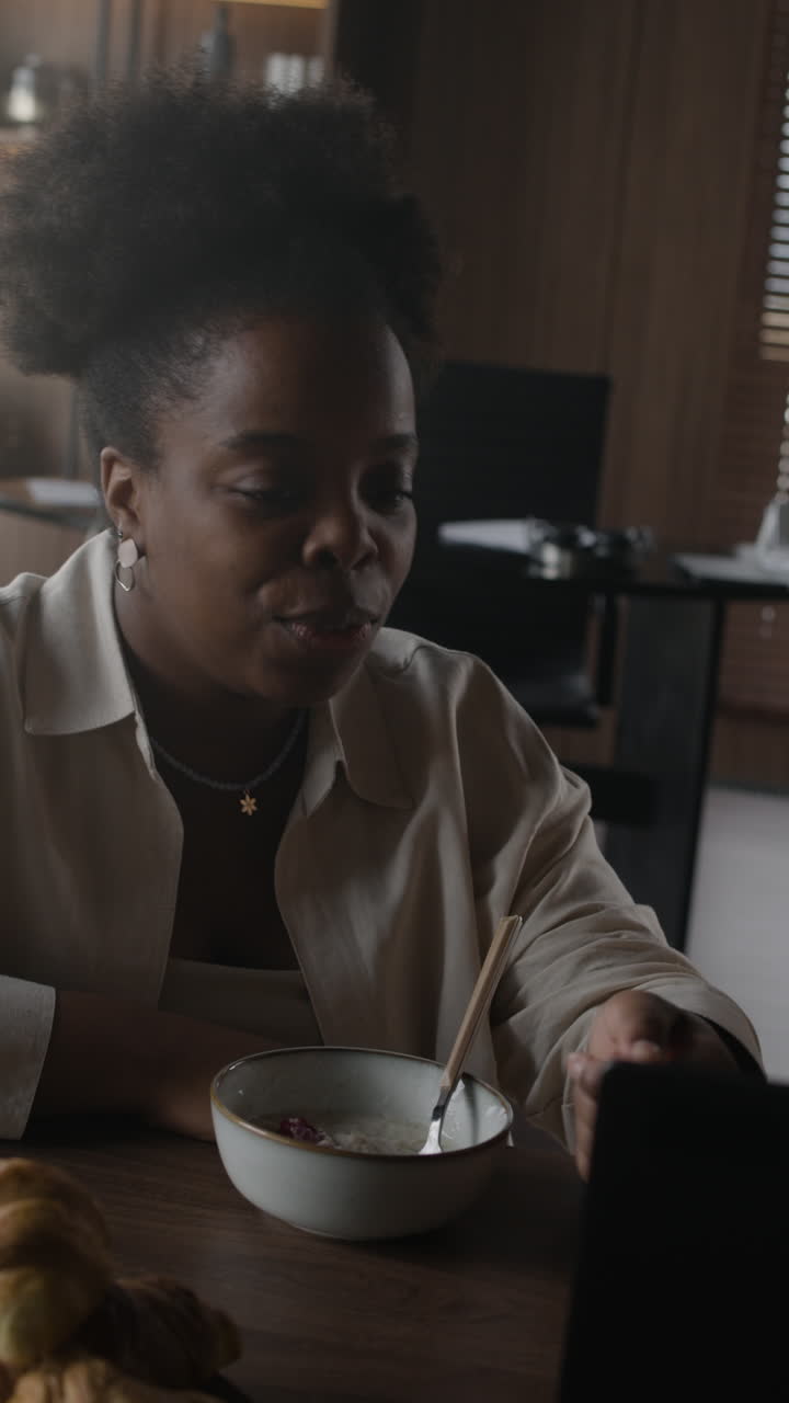 mujer comiendo el desayuno mientras trabaja en la computadora portátil