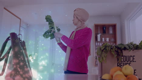 Biracial-woman-in-hijab-looking-at-vegetables-in-kitchen-over-spots-of-light