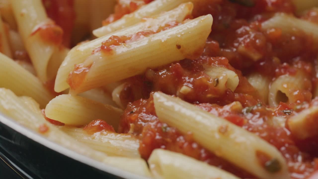 Stirring Penne Pasta with Tomato Sauce in Frying Pan