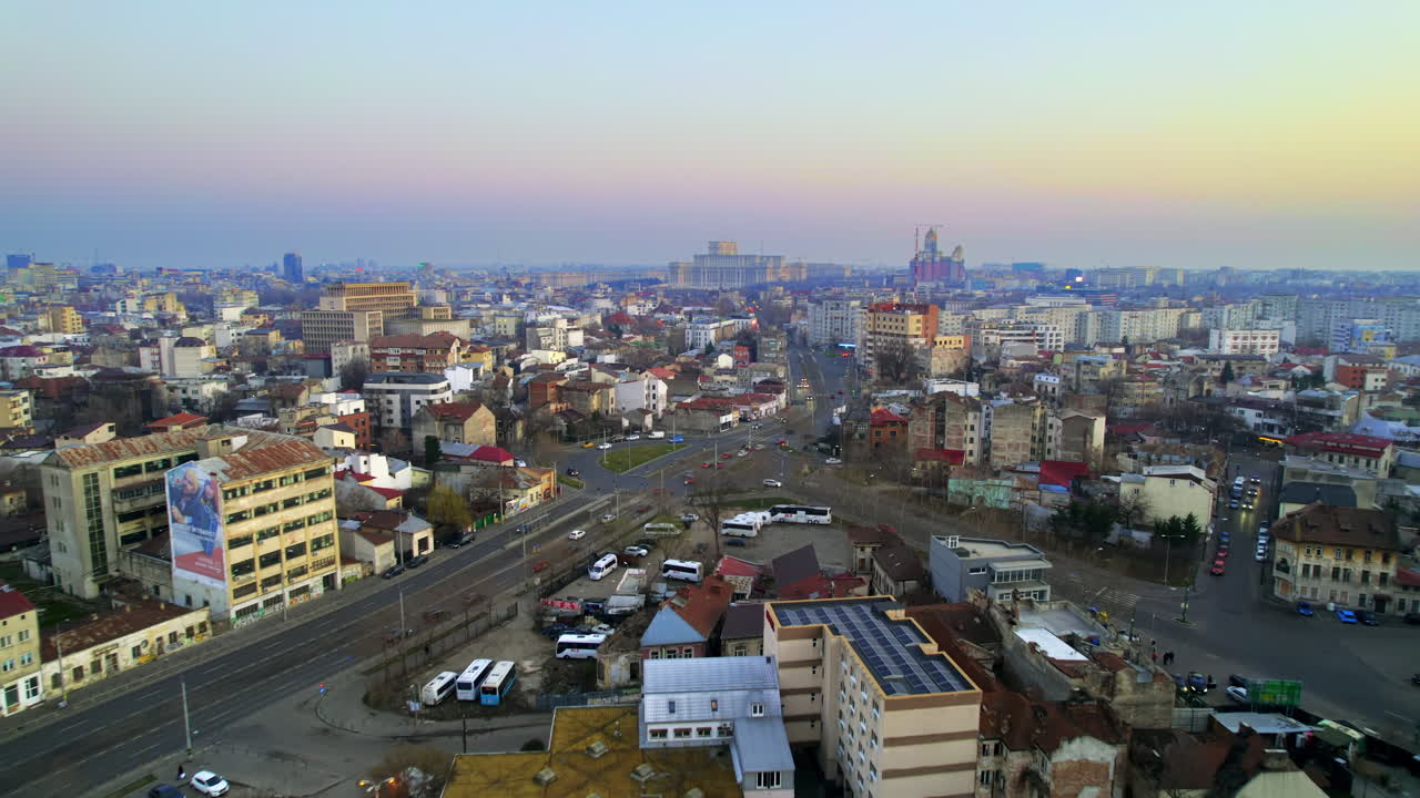 Aerial drone view of Bucharest at sunset, Romania. Palace of the Parliament in the distance, multiple buildings, moving cars