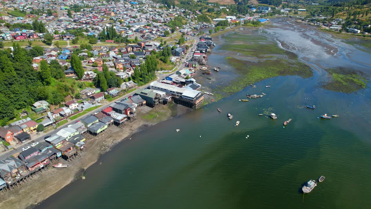 drone aéreo sobre la vía fluvial de castro con barcos y casas tradicionales, chile chiloe, 4k