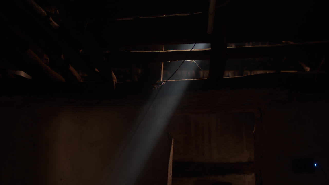 A beam of sunlight appears blue as smoke from a cooking fire drifts through it