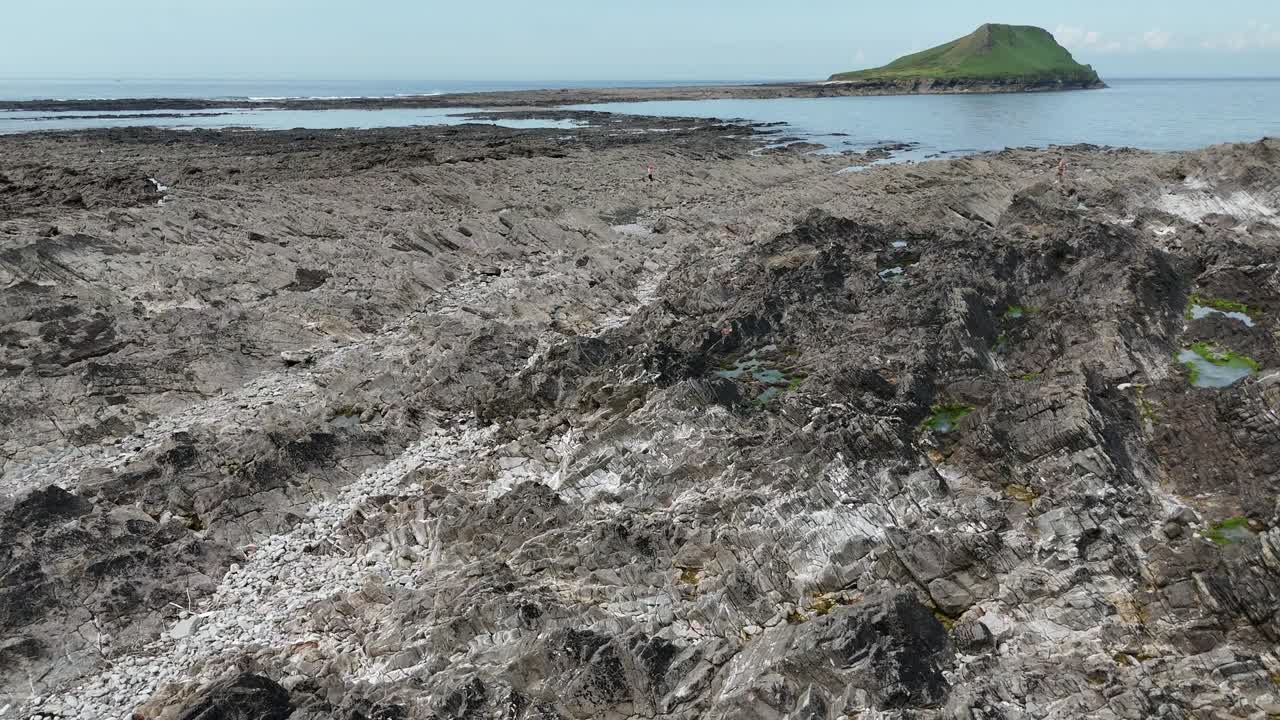 Aerial drone shot showcases dry, rocky landscape beside lake in England, UK. The rugged terrain and tranquil water create stark yet beautiful contrast