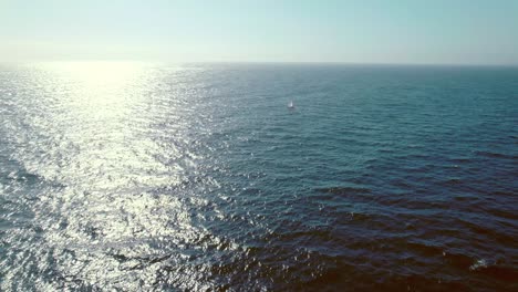 Drone-dolly-in-flyover-of-a-lonely-sailing-boat-at-sea,-lonely-and-reflective-place