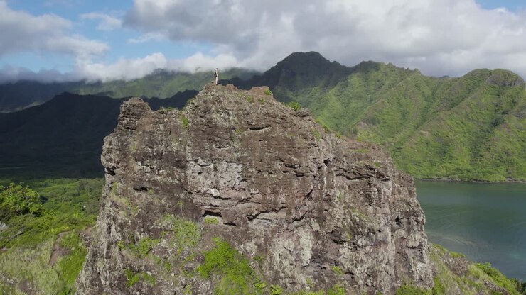 Oahu, Kahana Koyu'na bakan uçurum kenarındaki dağ zirvesinde yürüyüşçü - Havadan Drone Çekimi