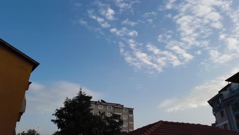 Lapso-De-Tiempo-De-Nubes-Blancas-Desde-Un-ángulo-Bajo-Moviéndose-Sobre-Edificios-Residenciales-Al-Atardecer