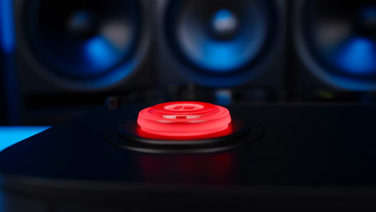 Illuminated red push button on black control panel with blue speaker backdrop during midsequence