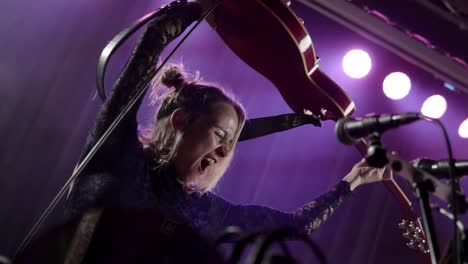 Closeup-of-an-excited-Professional-guitarist-singing,-screaming-and-performing-in-night-club-lights-close-up