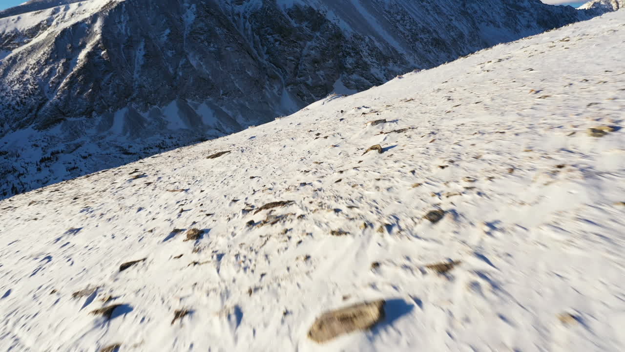 화창한 겨울날 눈 위를 걷는 트레킹 폴과 쇼슈즈를 신은 사람의 역동적인 공중 전망, 액션 드론 샷