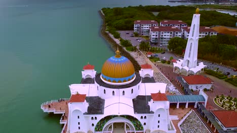 Toma-Aérea-Inclinada-Hacia-Abajo-Del-Hermoso-Edificio-De-La-Mezquita-Del-Monumento-En-Melaka,-Flotando-En-El-Agua