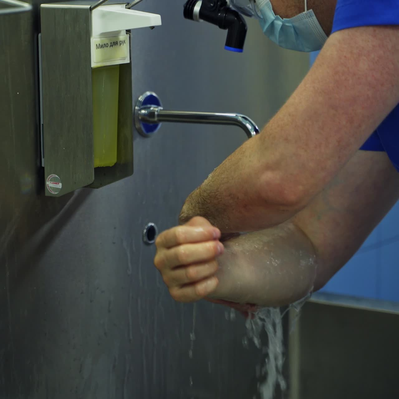 Careful proper hand washing near a big metal sink. Male doctor getting ready for surgical operation