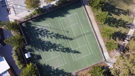 aerial rotating view over two tennis courts surrounded by trees