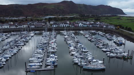 scenic luxurious waterfront harbour apartment village yachts and sailboats under mountain coastline aerial view descend right orbit