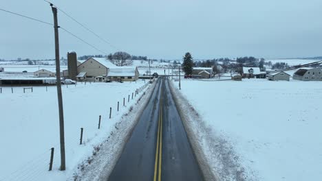 rural road in american countryside covered in snow during winter