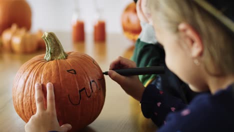 close up of girl drawing on pumpkin