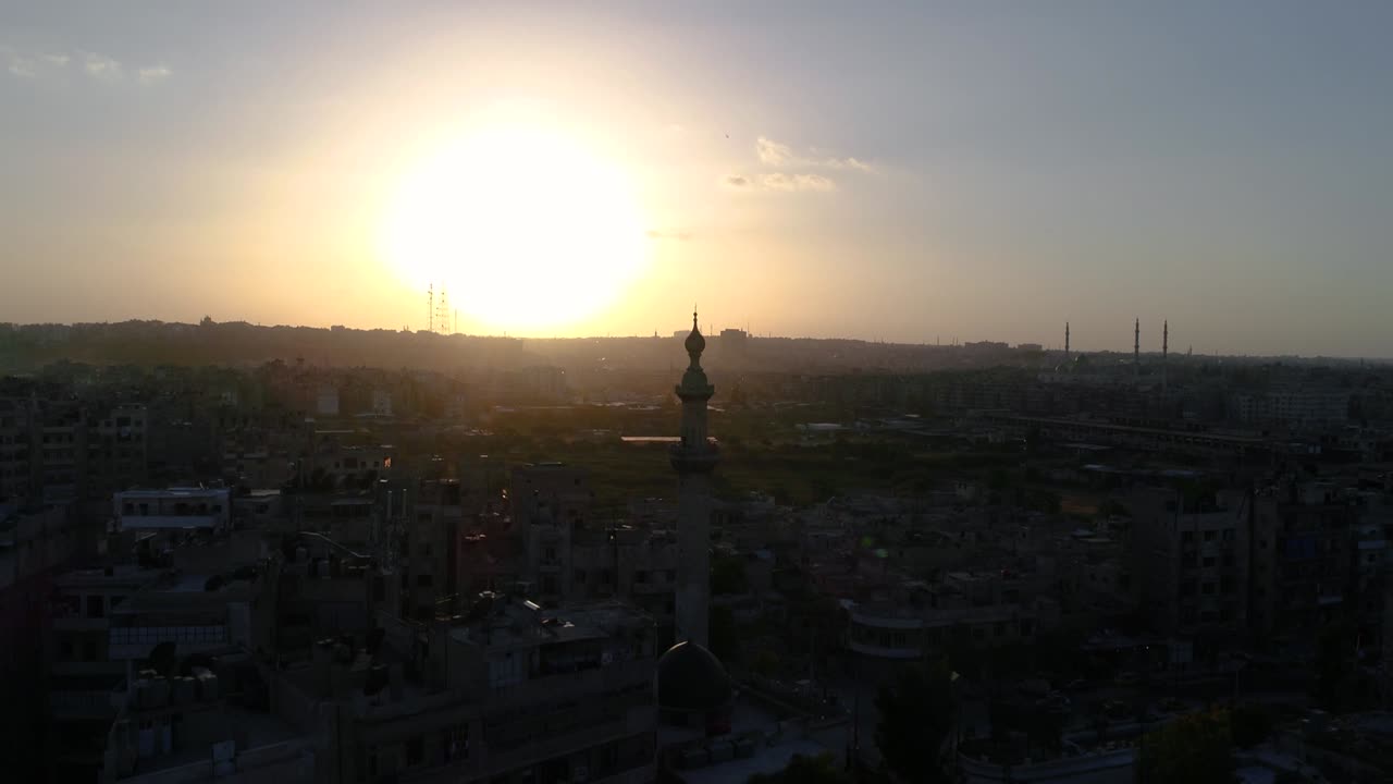 vista aérea sobre una mezquita siria bajo la puesta de sol. podemos ver la ciudad de alepo en todo el horizonte 4k