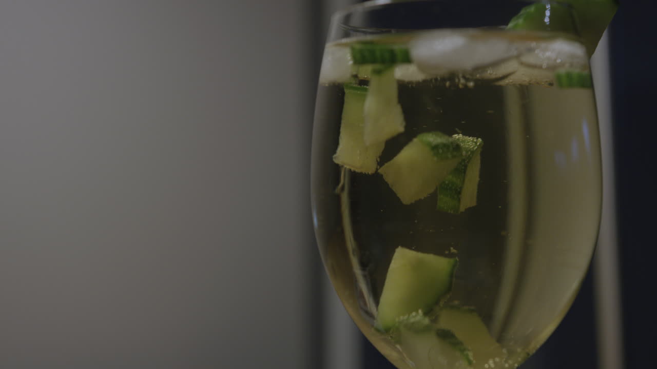 un primerísimo plano de trozos de pepino en un vaso de sangría a cámara lenta