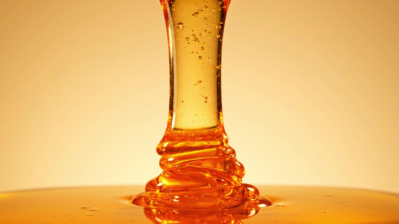 Miele dorato denso che cola e si avvolge su una superficie piana