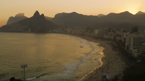 drone descending over ipanema beach rio de janeiro brazil at sunset, ocean reflection, skyscrapers, mountains background