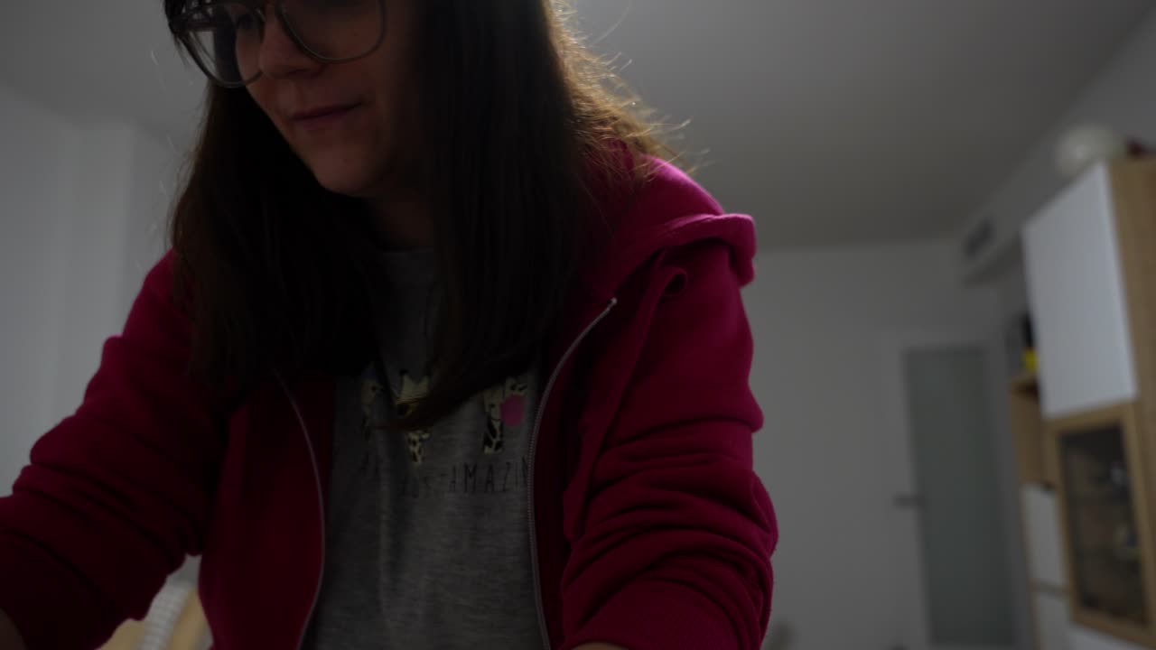 Smiling pregnant woman hangs Halloween-themed baby clothes in cozy living room