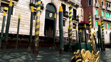 golden horse ornament in front of a gondola cruising through the venetian canal - close up shot