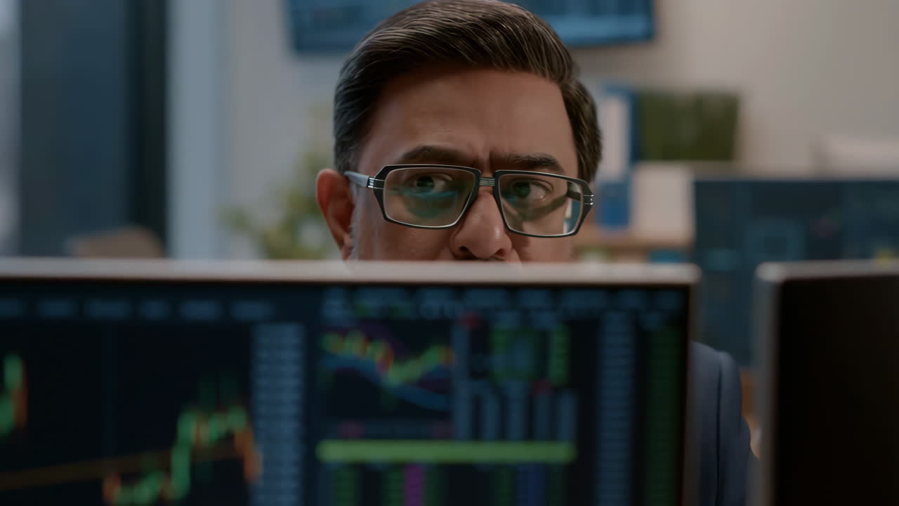 A man analyzing financial data and stock market charts on a computer monitor