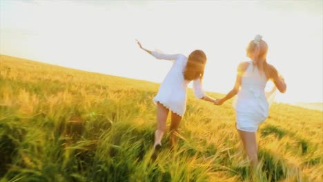 two women running through a wheat field at sunset