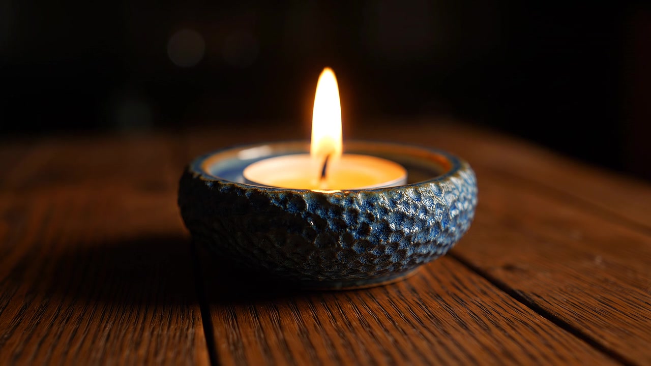 Calda luce di candela in un portacandele in ceramica blu testurizzata