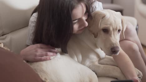 Pretty-female-brunette-in-white-T-shirt-hugging-her-dog-pet-and-trying-to-kiss-for-taking-a-selfie