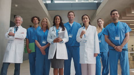 portrait of multi-cultural medical team wearing uniform standing inside hospital building