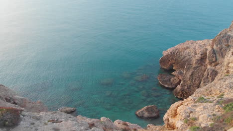 Toma-Circular-Constante-Capturada-Con-Un-Dron-Cerca-Del-Borde-Del-Acantilado-Rocoso,-Paisaje-De-Agua-De-Mar-Azul