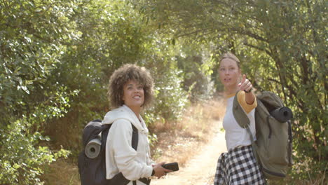 young biracial woman with curly hair and a young caucasian woman with blonde hair are hiking