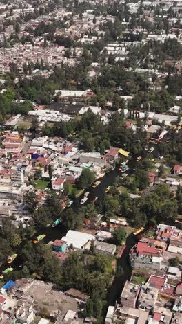 Sunlit-drone-perspective-of-Xochimilco-trajineras-in-vertical-orientation