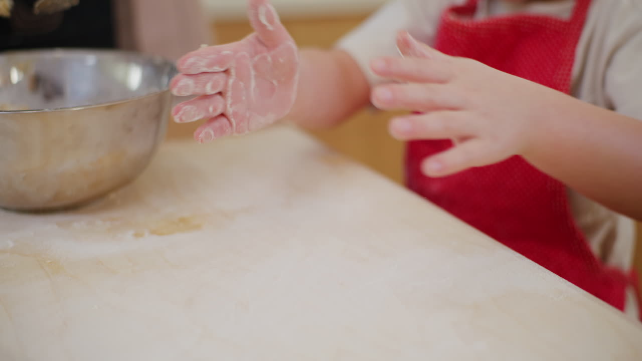 niño frotando harina en una tabla en la cocina preparándose para hornear