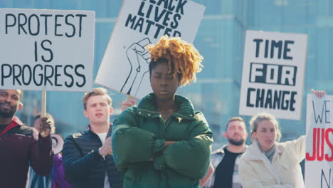 portrait of female protestor amongst marchers with placards on black lives matter demonstration