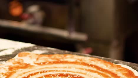 close-up of hands grating cheese onto a pizza with tomato sauce spirals.