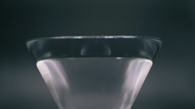 Peperoni rossi e gialli che cadono in un bicchiere facendo fuoriuscire l'acqua al rallentatore - Primo piano