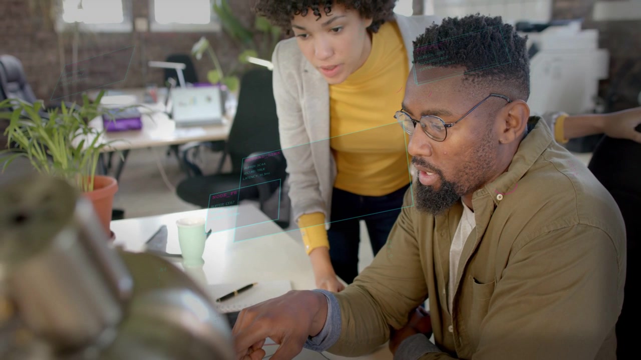 Woman pointing over laptop, launching animated business charts while man typing and reviewing data