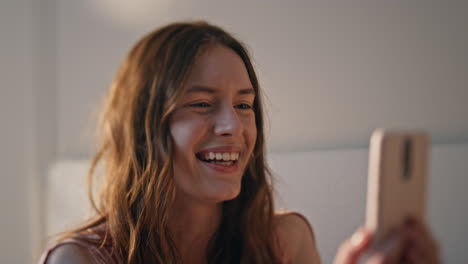 smiling teenager talking video call at home closeup. joyful girl holding mobile