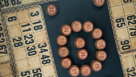 Filmische-Nahaufnahme,-Sanftes-Herauszoomen,-Rotierende-Aufnahme-Von-Oben-Auf-Bingo-Holzfässer-Im-Kreis,-Holzige-Figuren,-Hintergrund-Mit-Alten-Zahlen,-Vintage-Brettspiel,-Professionelle-Beleuchtung,-Zeitlupe-120-Fps