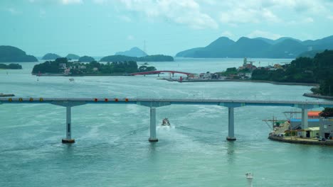 aerial view of boat cruising in the ocean passing under geoje bridge in south korea